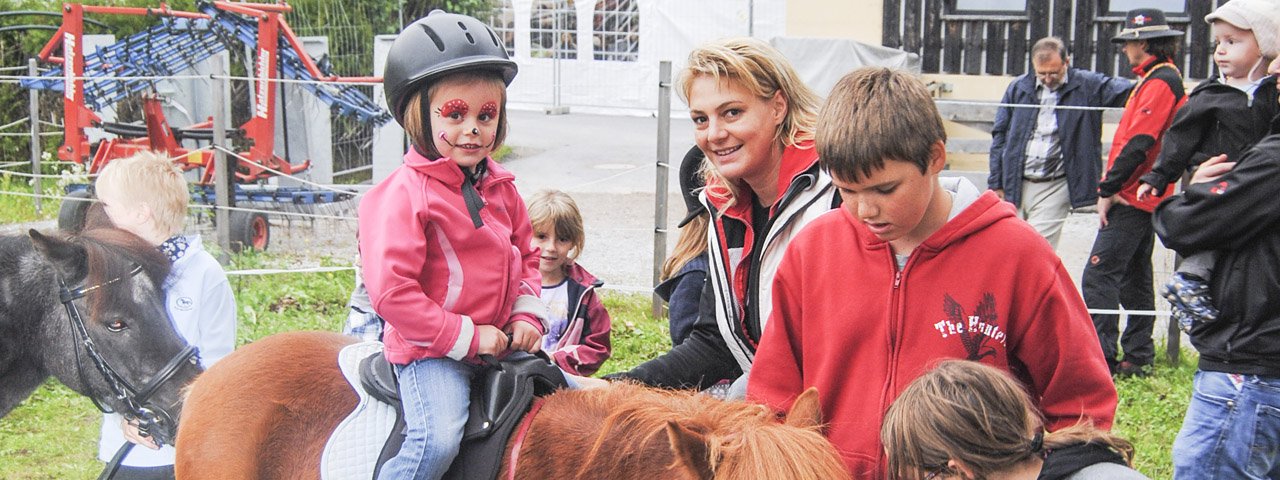 Kinderen vermaken zich tijdens het schilderen, ponyrijden en springen op het springkasteel, © Feuerwehr Wildermieming